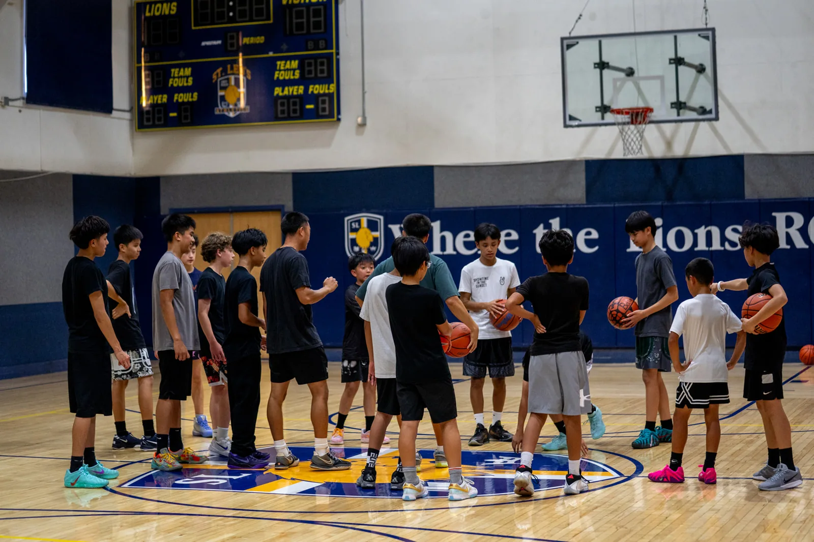 Coach Elijah running a session with athletes gathered on the court at By Any Means San Jose